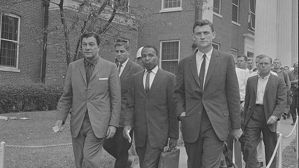 Photograph shows James Meredith walking on the campus of the University of Mississippi, accompanied by U.S. marshals. - Library of Congress